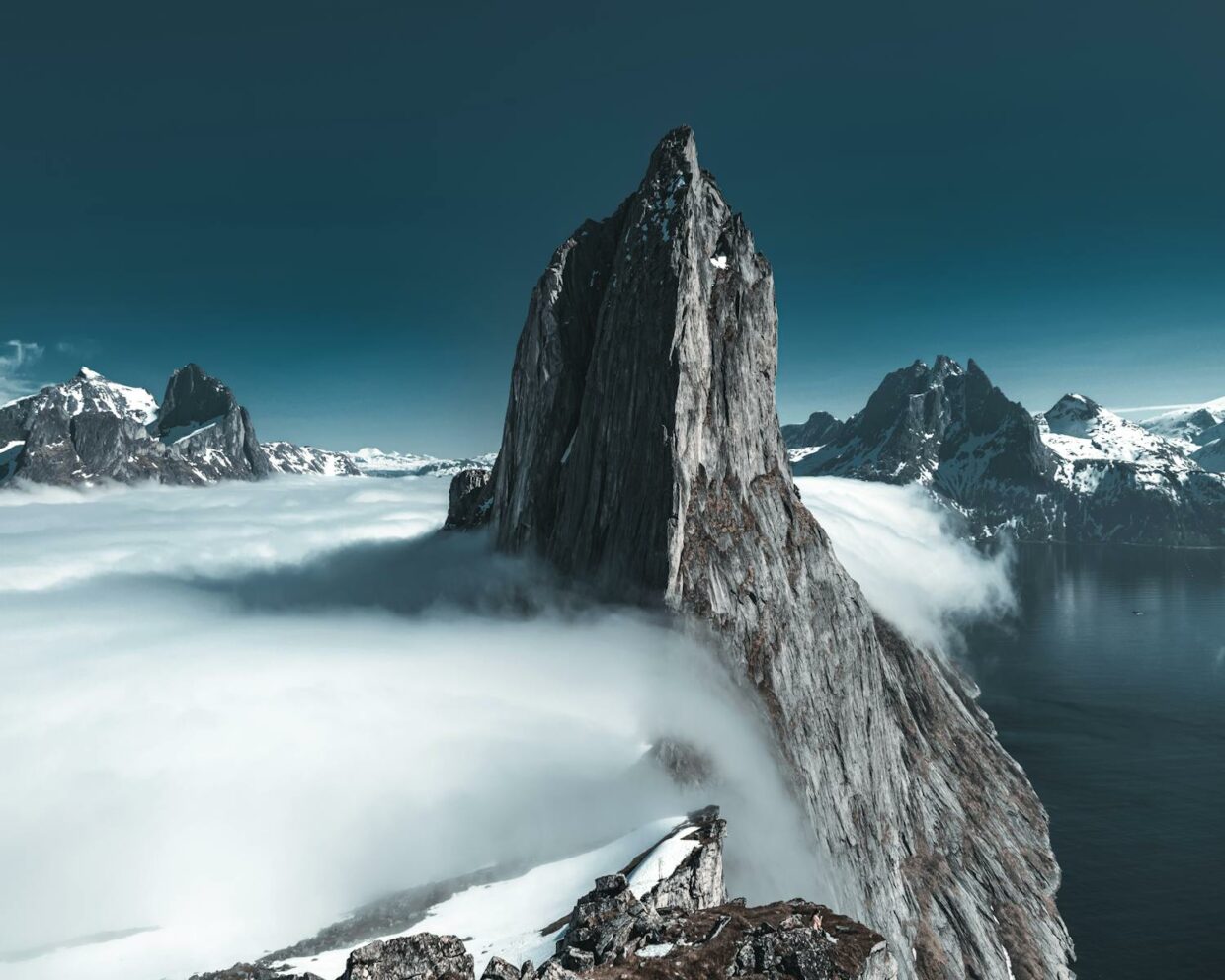 A stunning, snow-capped mountain peak rising above the clouds, creating an epic natural landscape.